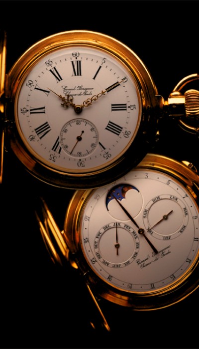 Two beautiful gold pocket watches with the covers opened exposing the white dial face and intricate time piece design against a black background.