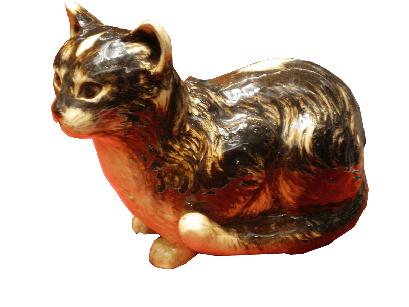 A brass colored statue of a a cat is seen in subdued light.